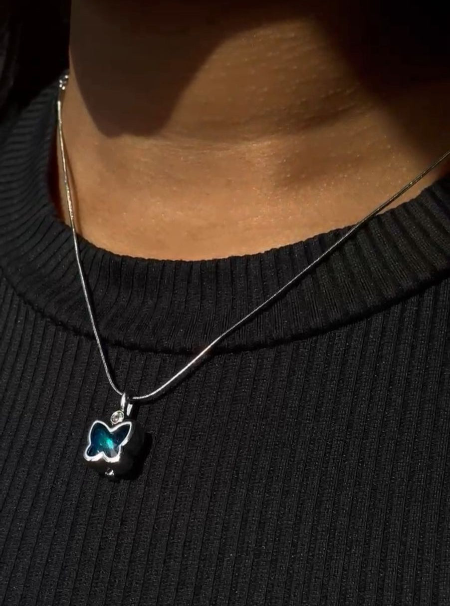 Necklace with a blue pendant worn by a person on a black background